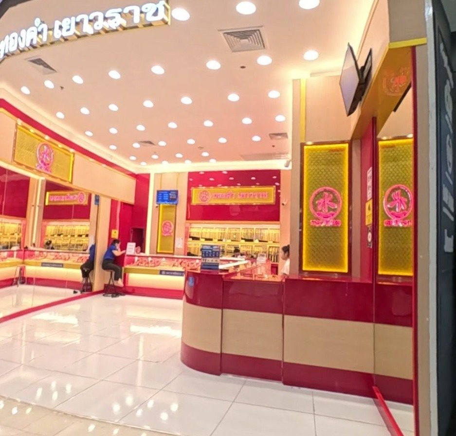 A Yaowarat-style gold shop: red and gold counters, lit gold displays, staff seated at the back.