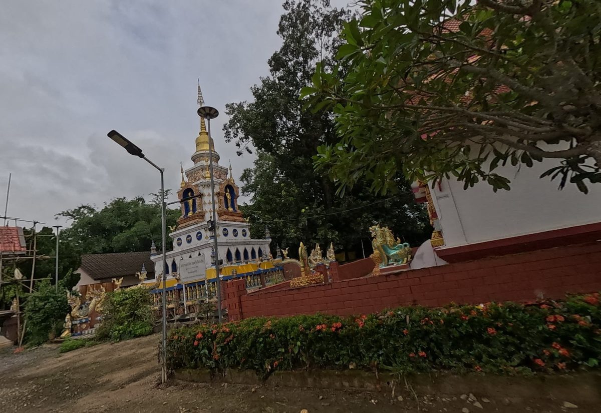 White-and-gold chedi with Buddha niches behind the viharn wall