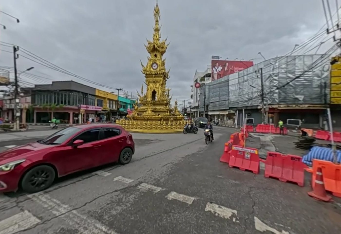 The clock tower from the approach road, with roadworks barriers and morning traffic
