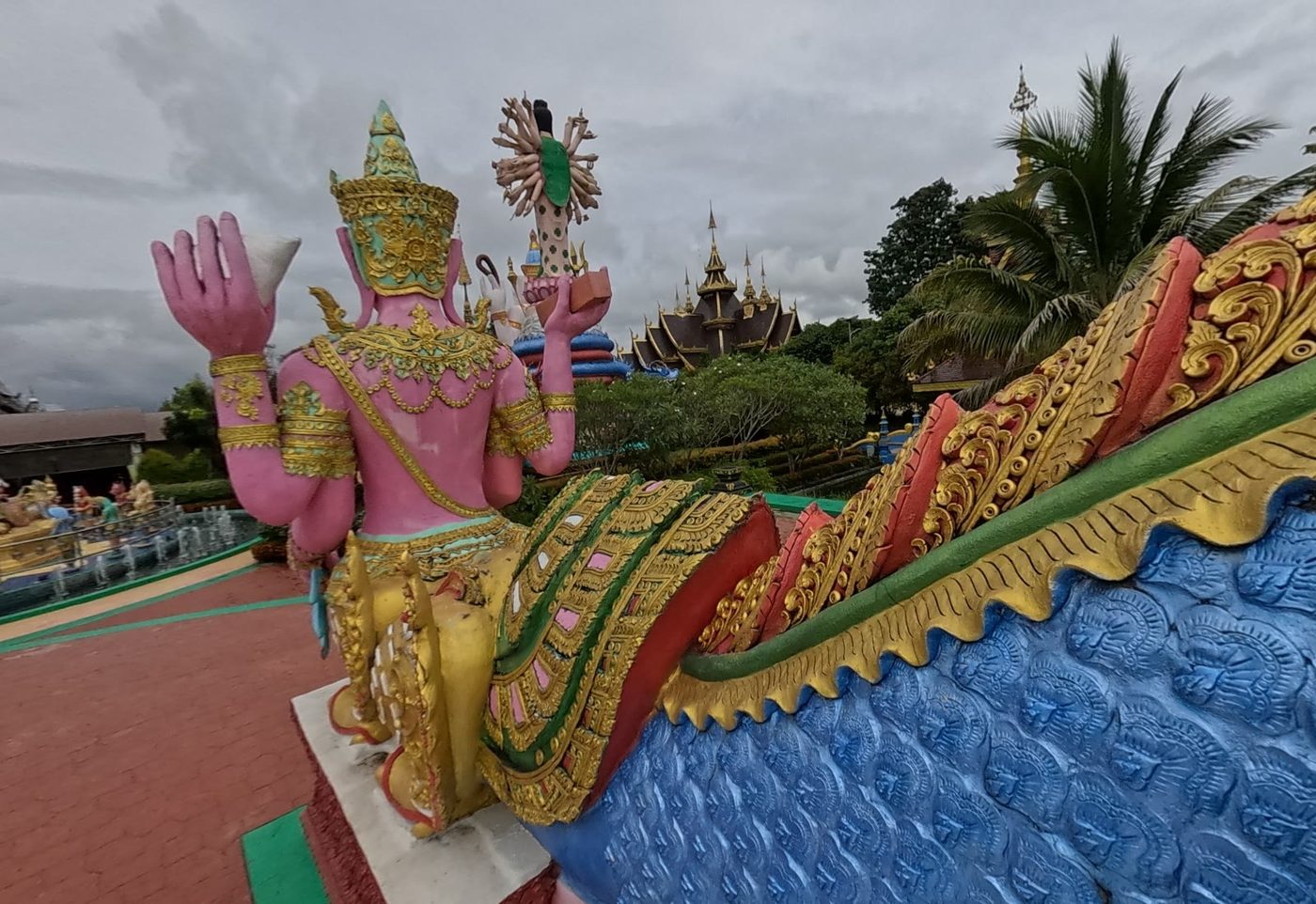 Pink deity on the naga balustrade, multi-armed statue and tiered roofs