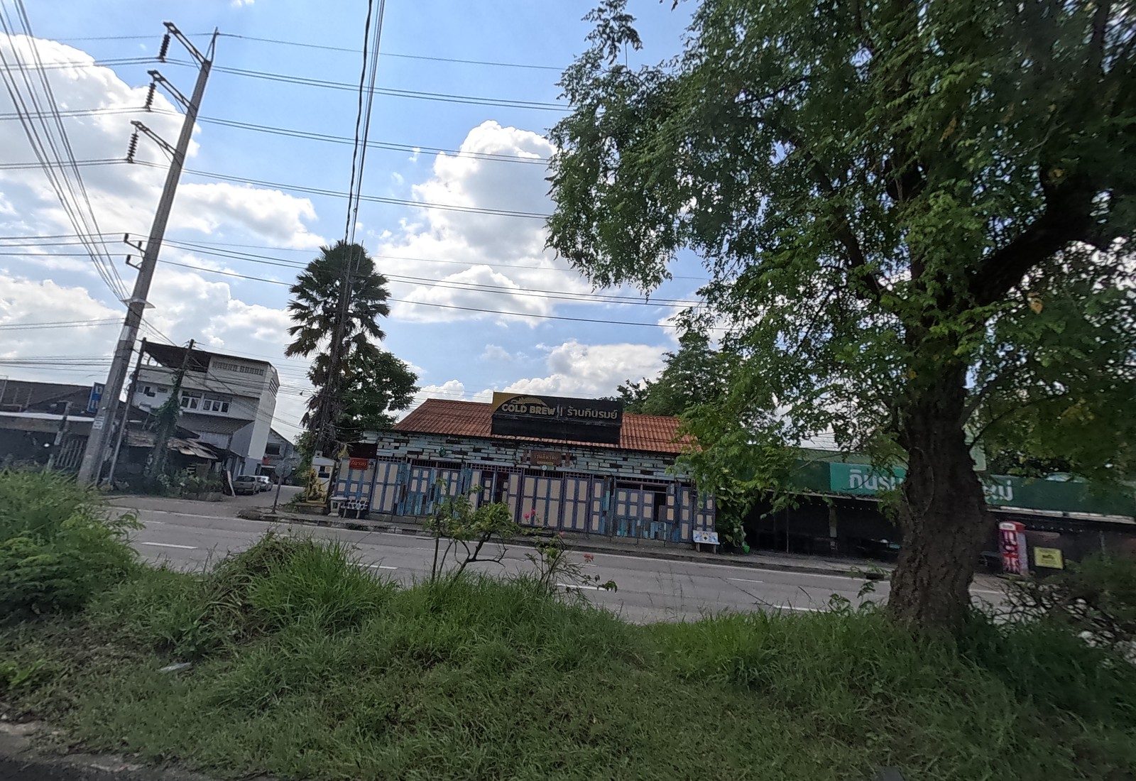 Across the road, the colourful wooden front of ร้านกินรมย์ with a COLD BREW sign, and the green กินรมย์ sign further along.
