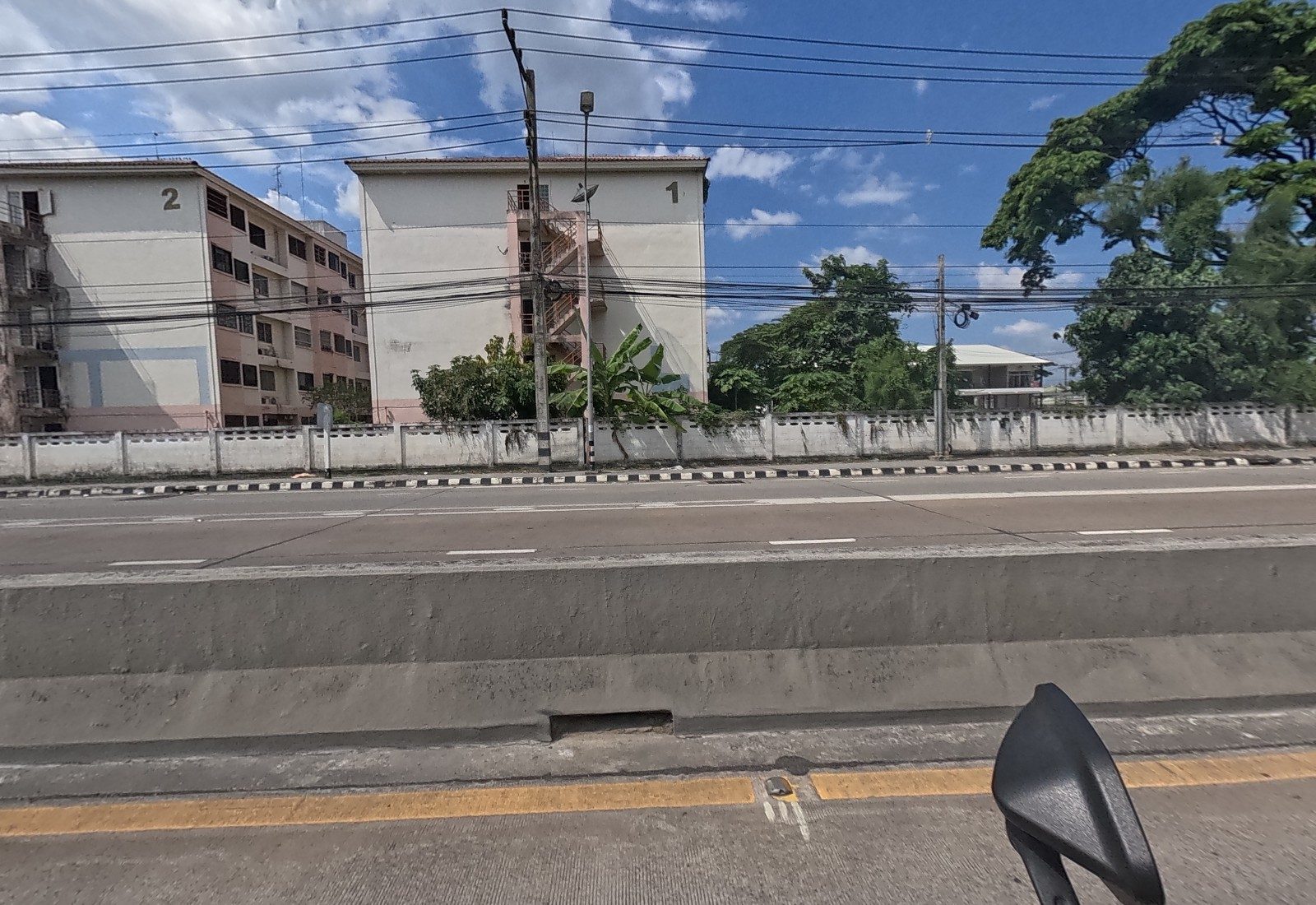 Across the median, Baan Ua Arthorn blocks 2 and 1 stand behind a low wall.