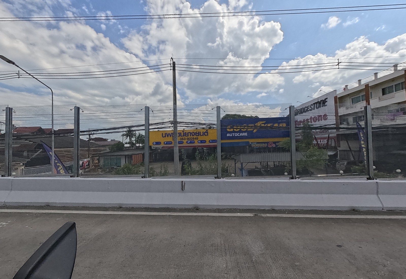 Below the flyover, the yellow-and-blue Goodyear Autocare tyre shop, with a Bridgestone/Firestone and Maxxis shop next door.
