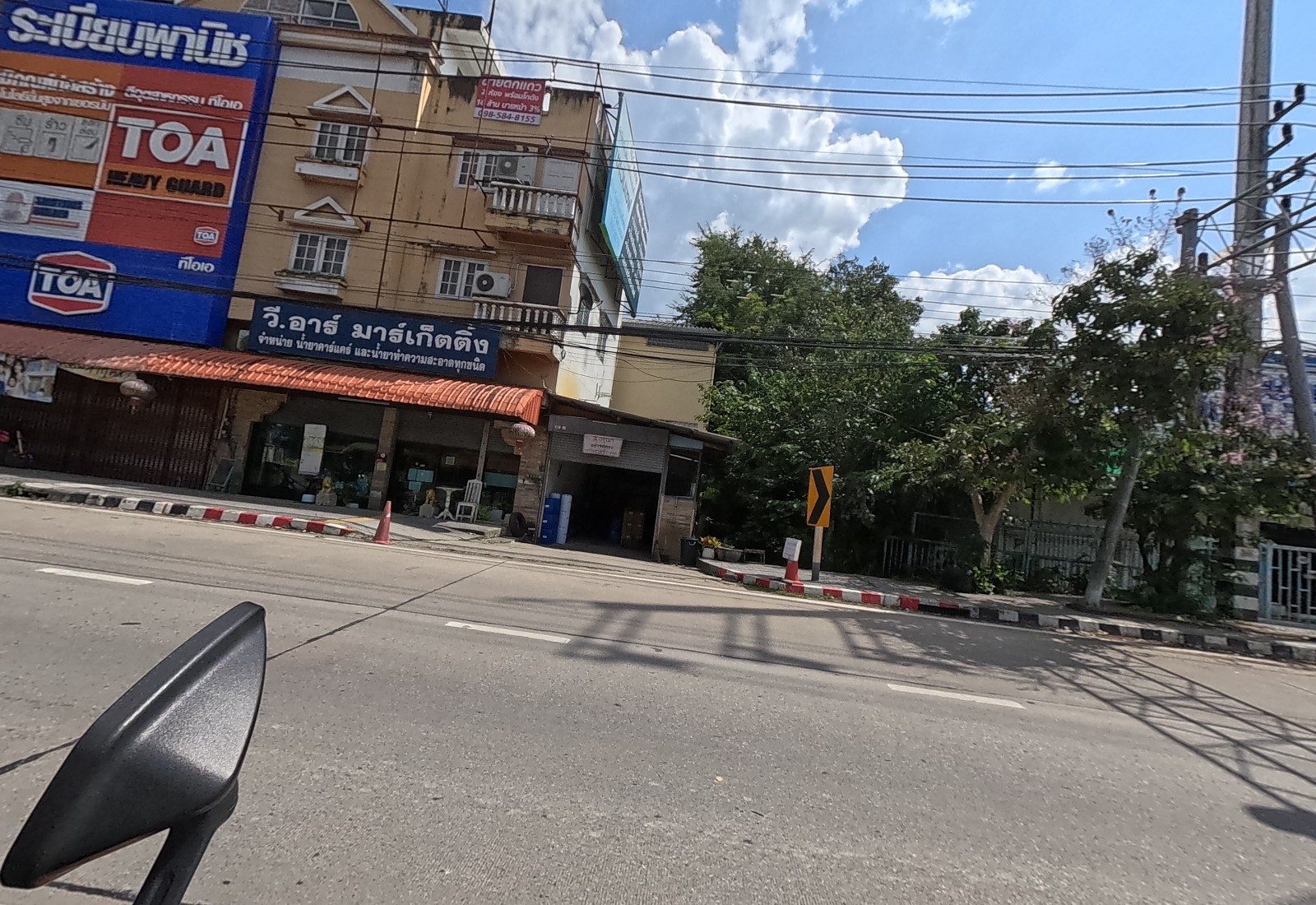 The TOA paint shop and a cleaning-products wholesaler under an orange awning, then trees at a bend.
