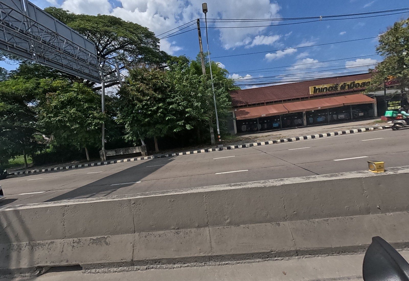 Across the road, big rain trees and the long brown-roofed second-hand clothes market.