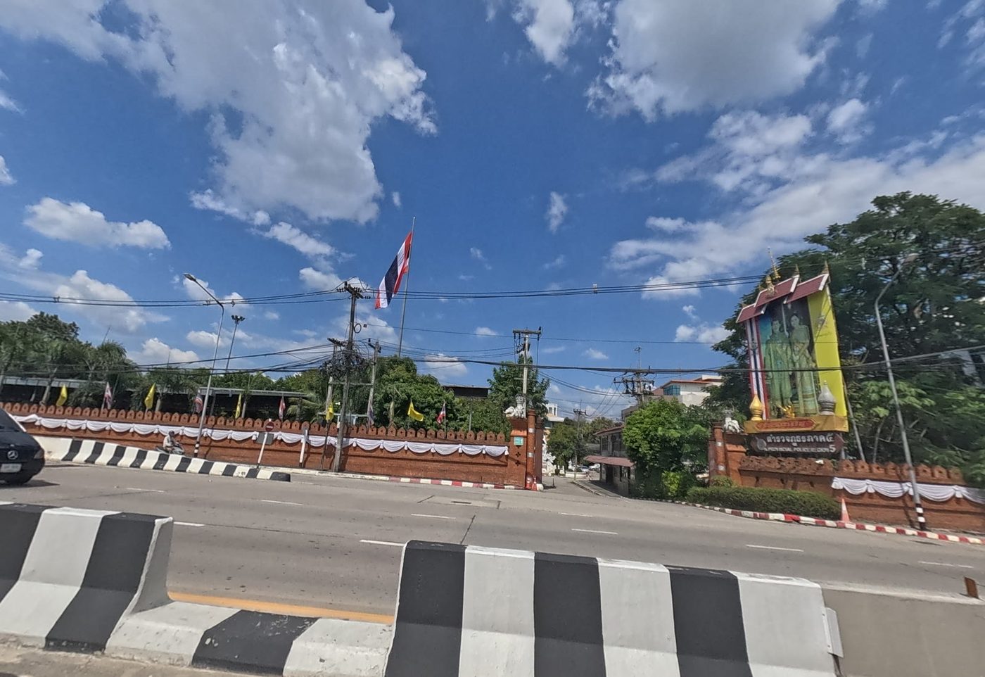 Gate of Provincial Police Region 5, with a red brick wall, a Thai flag and a royal portrait