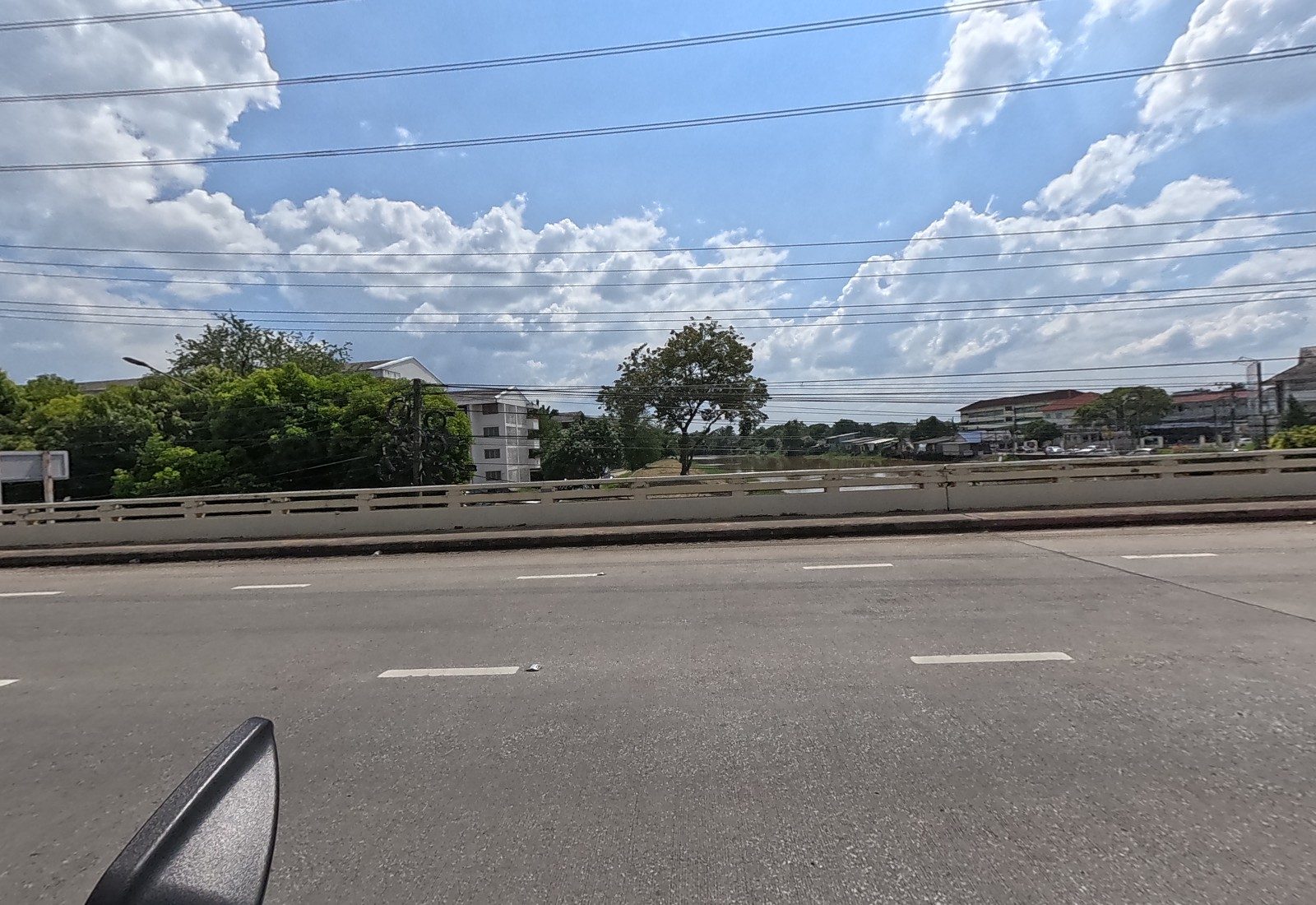 Looking over the bridge parapet onto the Ping River, with flats and a school-like building on the far bank.