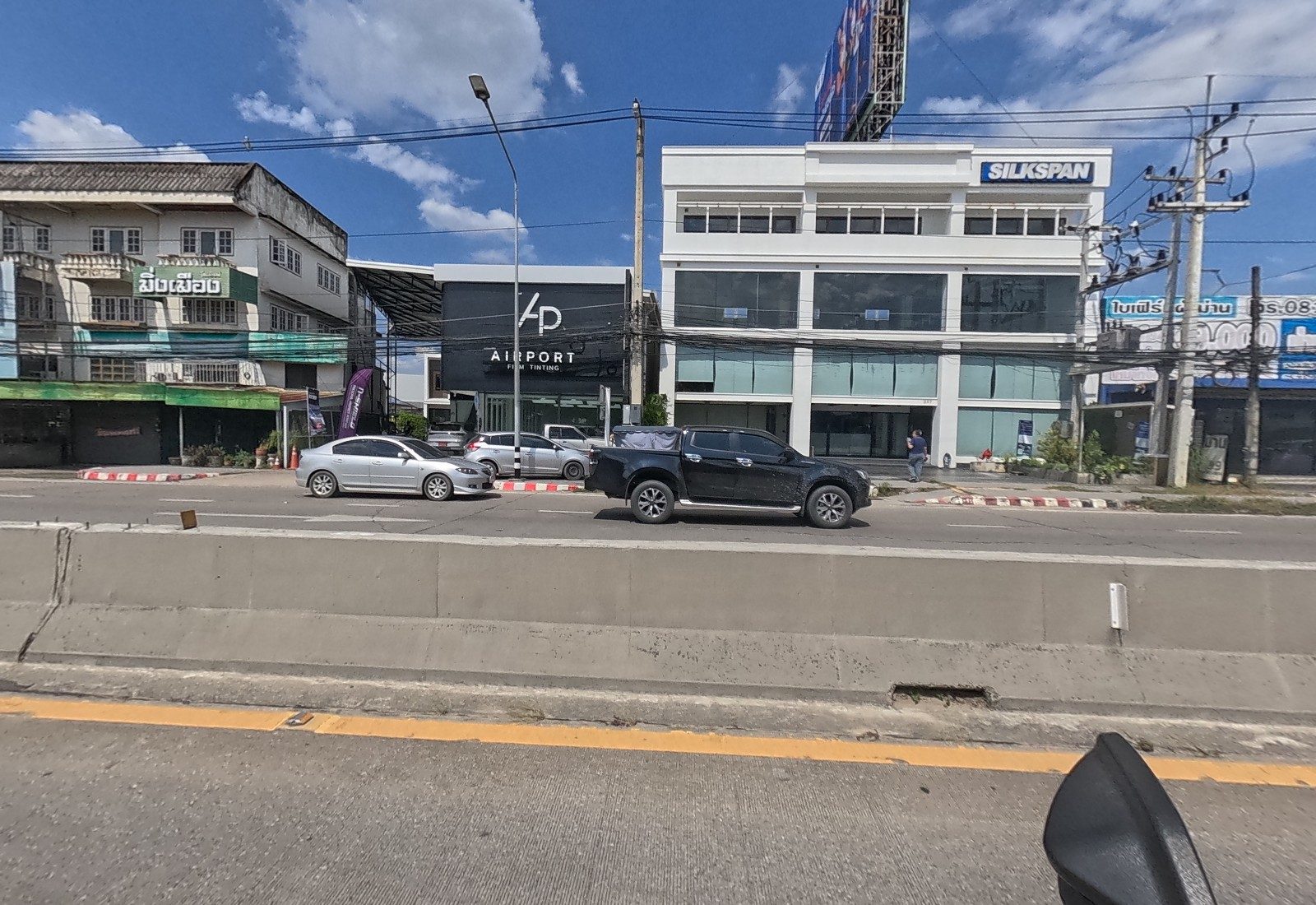 Across the road, the Ming Mueang shophouse, the black AP Airport Film Tinting showroom and the white Silkspan building.