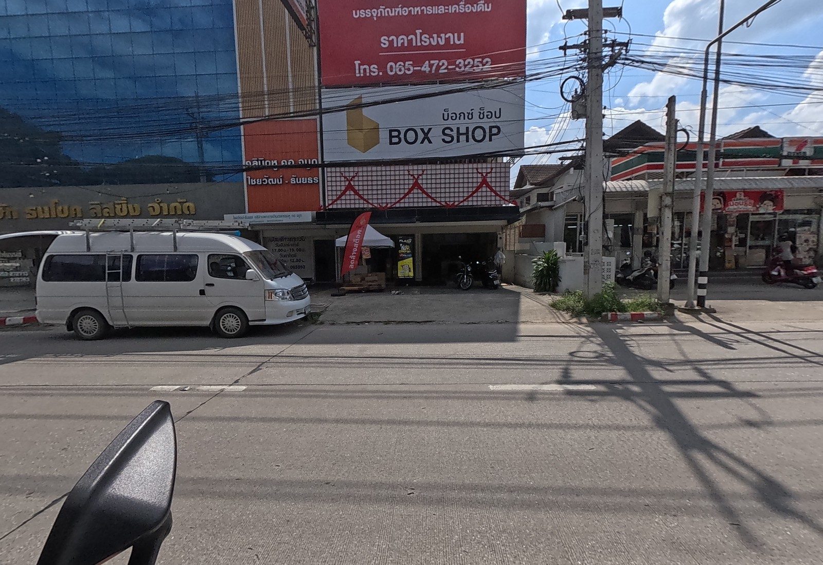 A white van is parked in front of Box Shop, a packaging shop under a big red sign, next to an ENT clinic sign and a 7-Eleven.