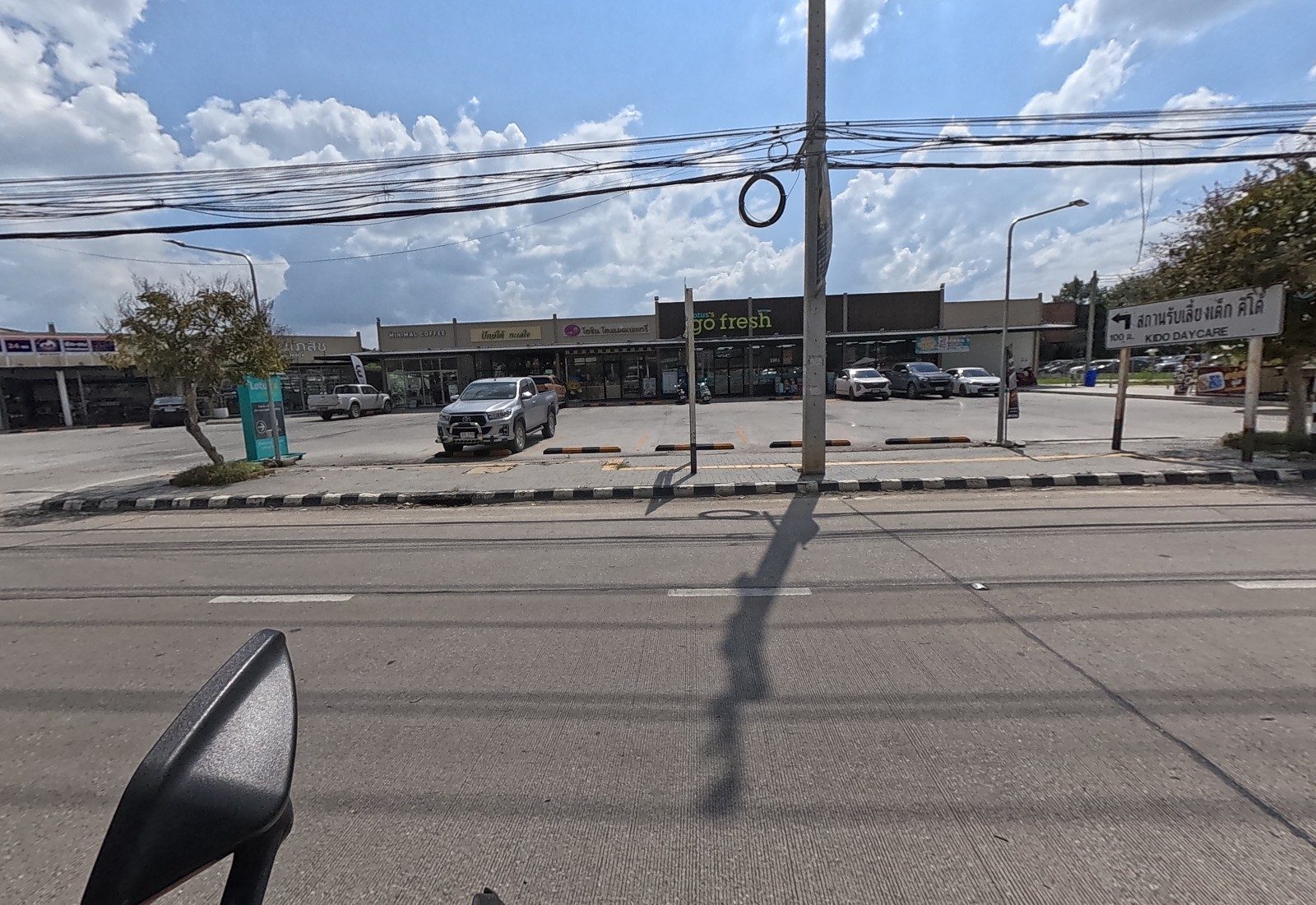 The Lotus's go fresh strip plaza sits behind its car park, with a Kido Daycare direction sign at the corner.