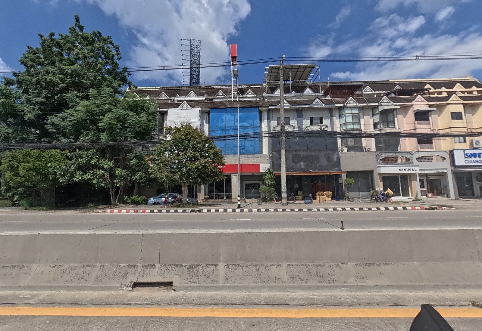 Across the median, townhouses hold a glass-fronted building with a red band, MINIMAL and an animal hospital sign at the right.