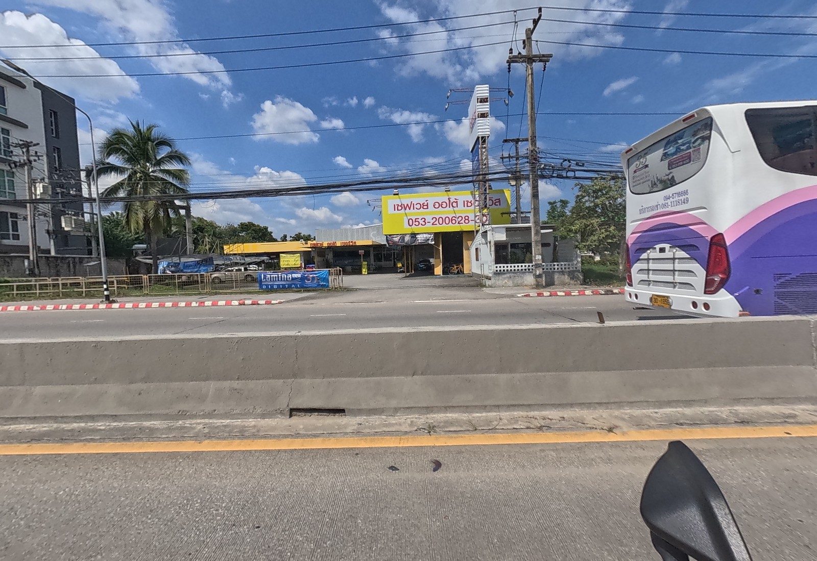 Across the road, the yellow Saveway Auto Service garage with a Lamina Digital film banner, and a tour bus passing.