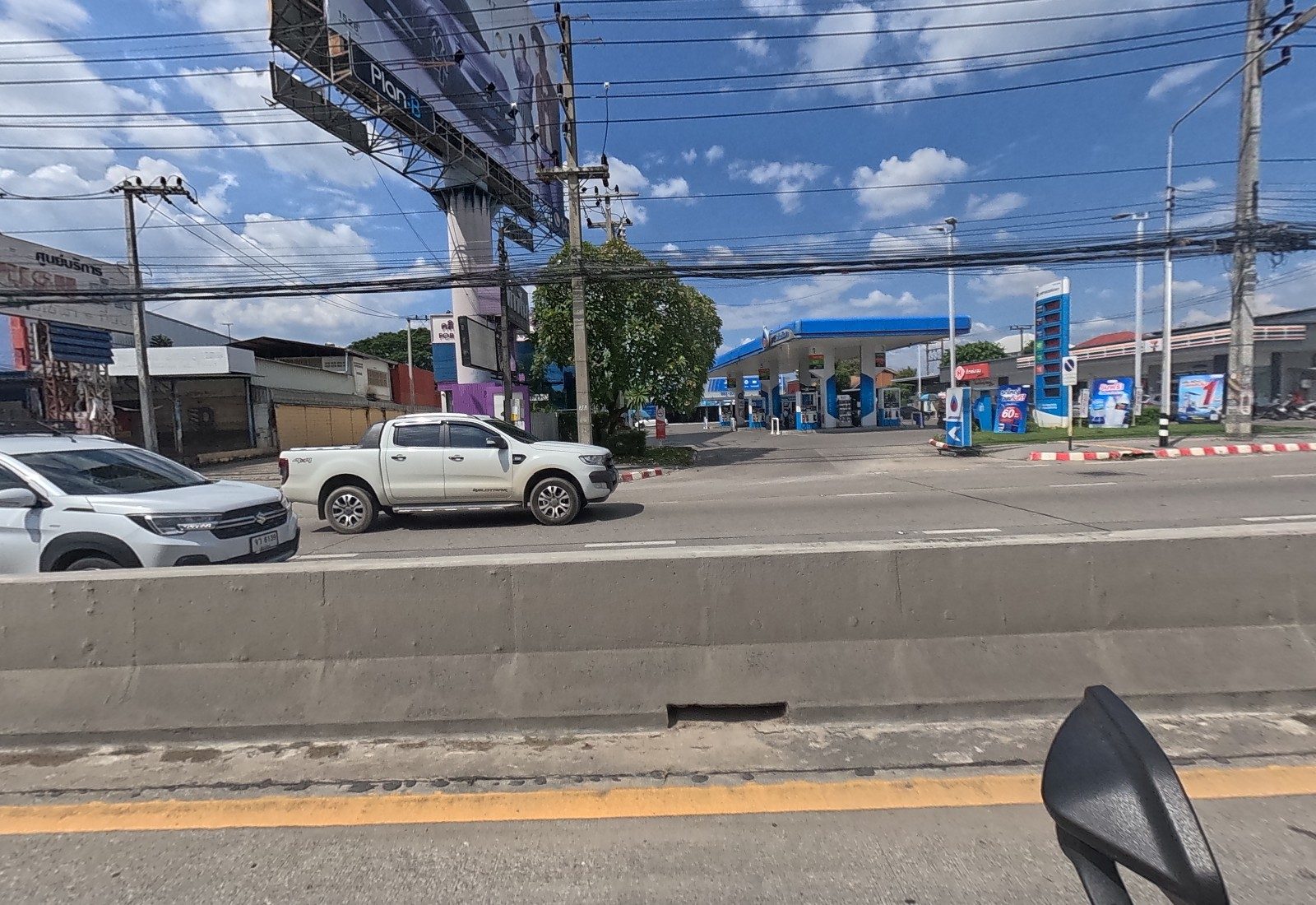 Across the road, a big car billboard, a PTT station with a 7-Eleven, and a purple-and-blue shop under the billboard.