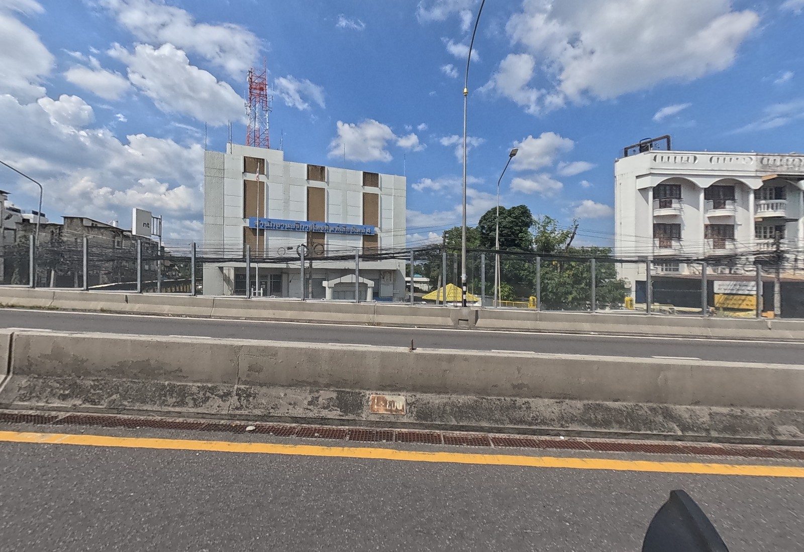 Across the median, the NT telephone service office with its radio mast stands beside a white arched building.