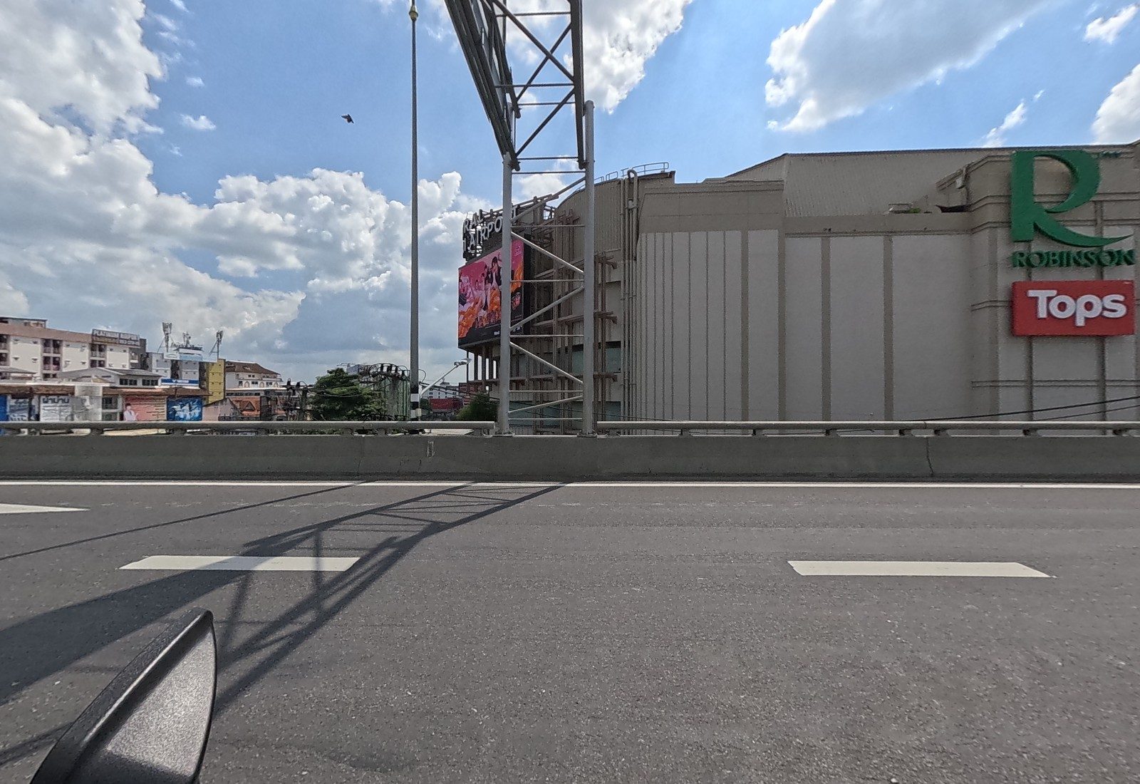 The windowless wall of Robinson with its green R and red Tops sign fills the left kerb, with the Platinum Airport building far left.