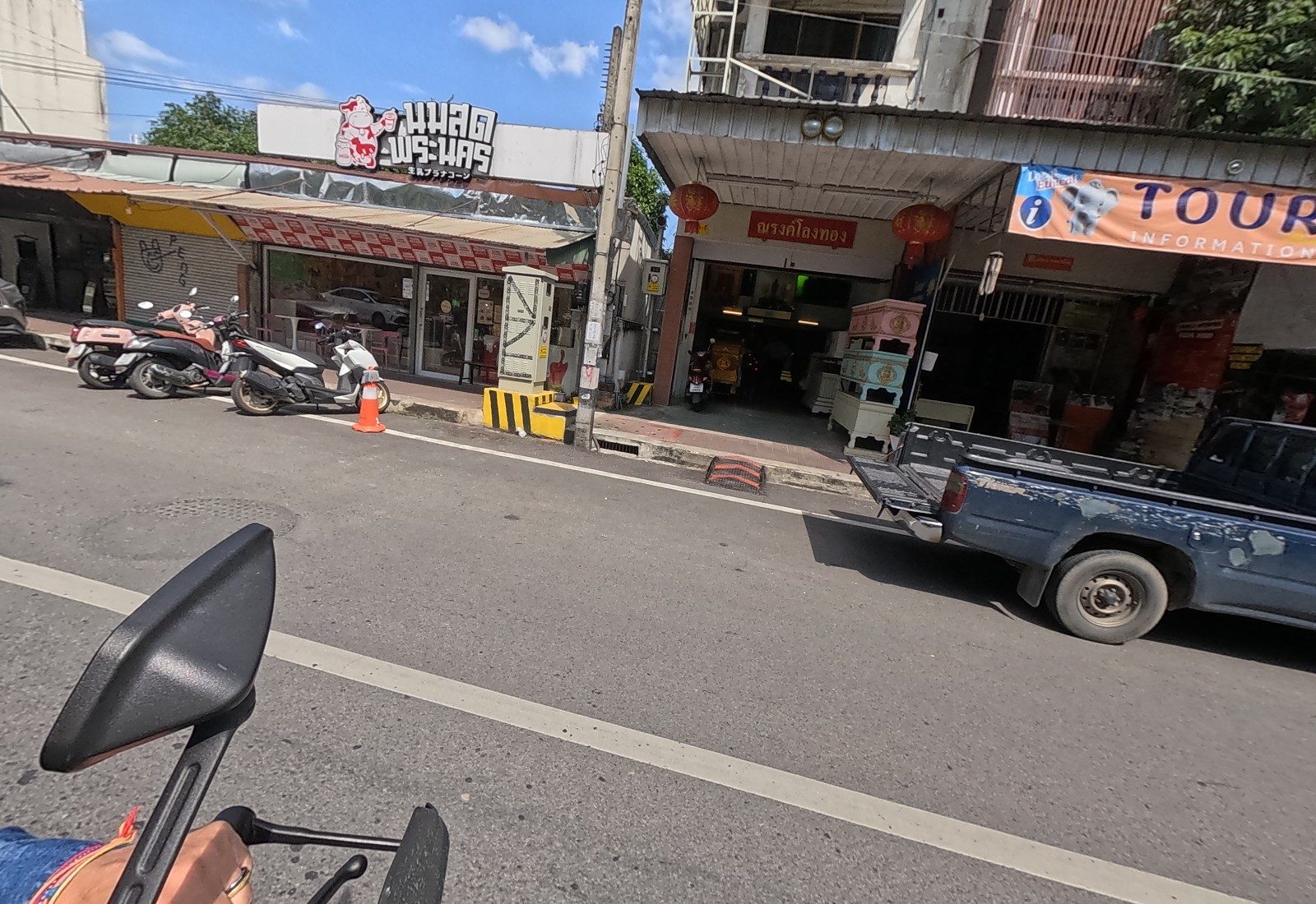 The นมสด พระนคร milk cafe with scooters out front, then a coffin shop with pastel coffins on display and a TOUR INFORMATION banner.