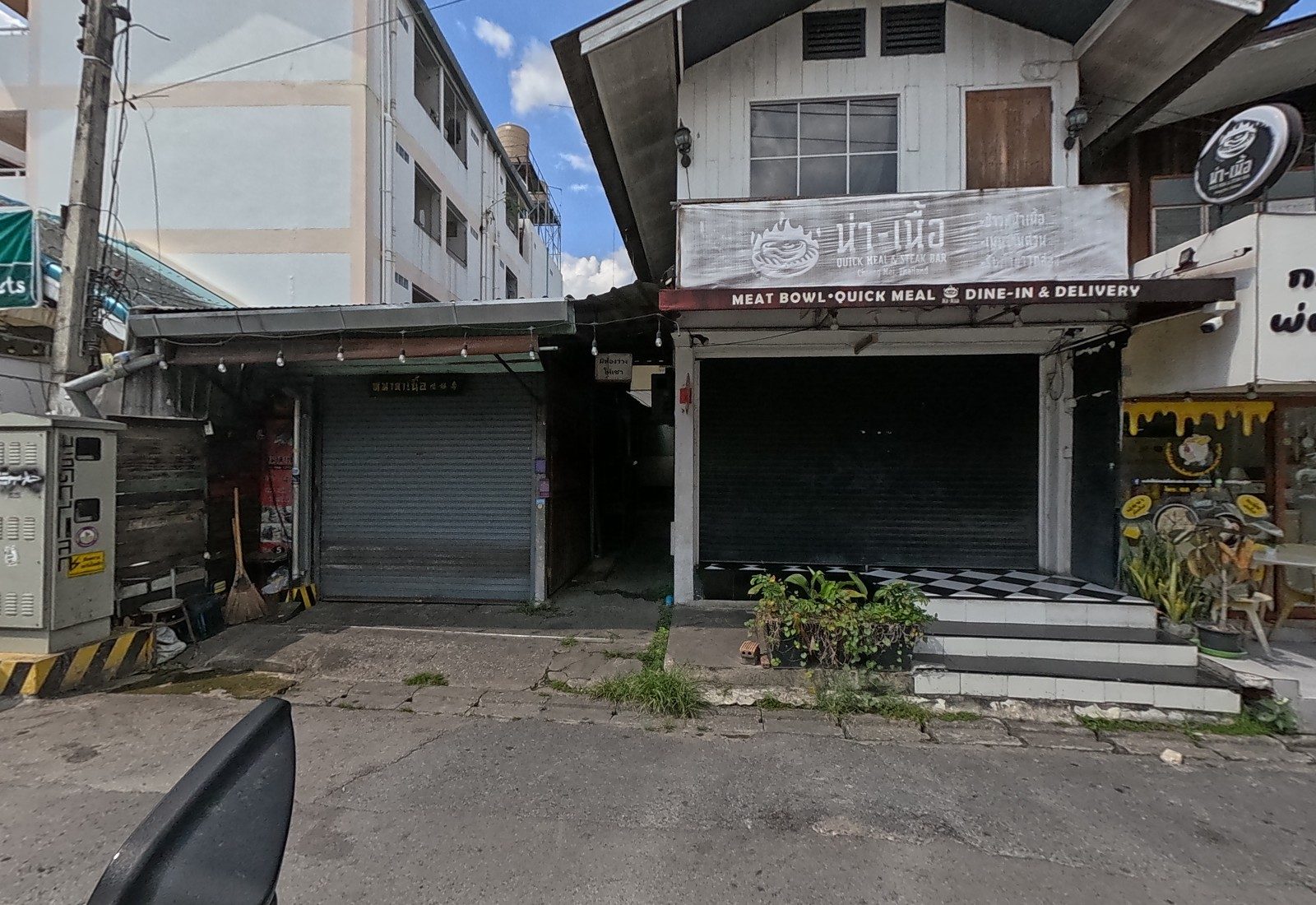 Shuttered shops: a tin-roofed unit, a room-for-rent sign on a passage, the น่า-เนื้อ steak bar and a cheese-chicken cafe.
