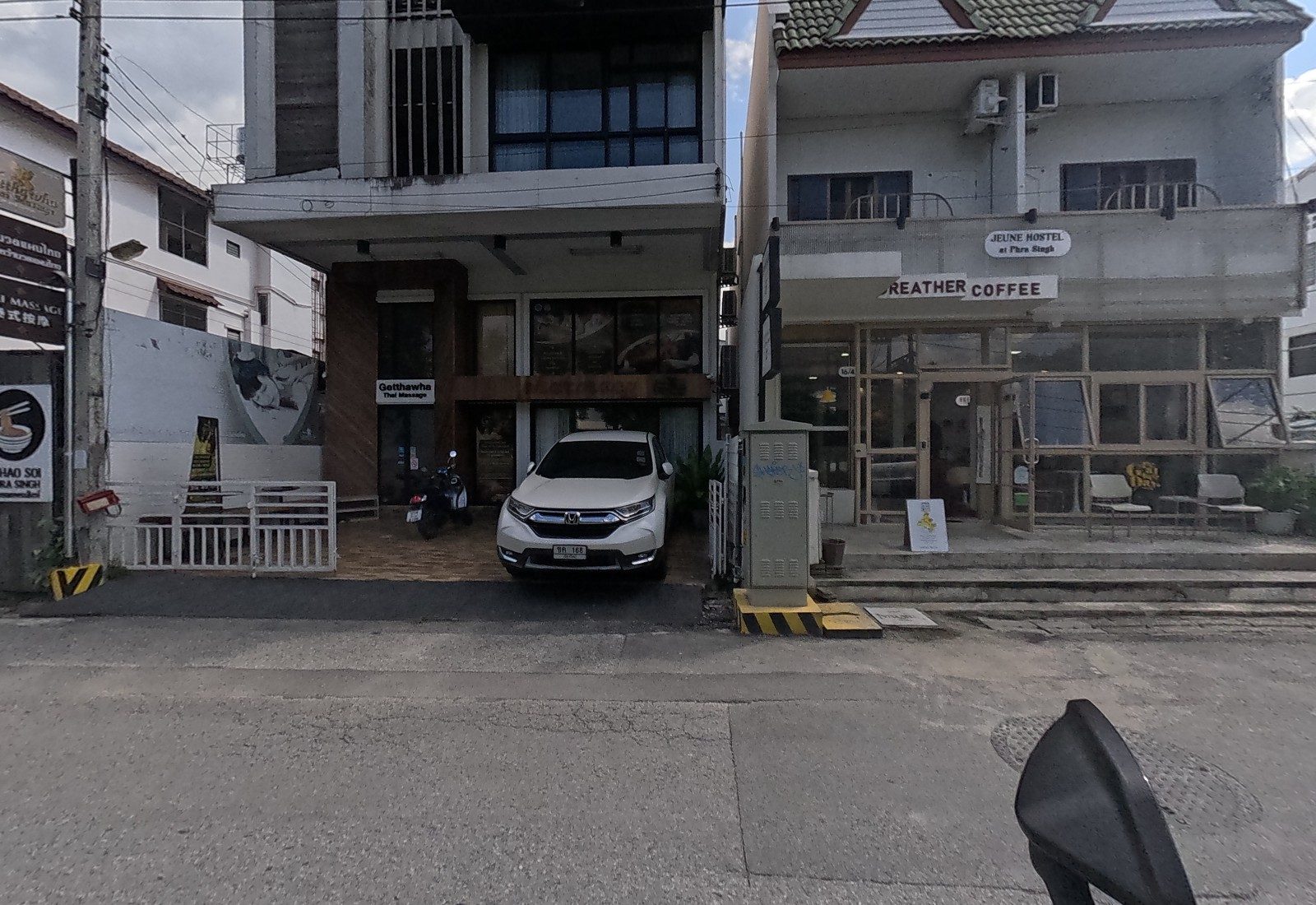Getthawha Thai Massage fronts a modern three-storey building with a white Honda parked inside the gate, next to Greather Coffee at 16/4.