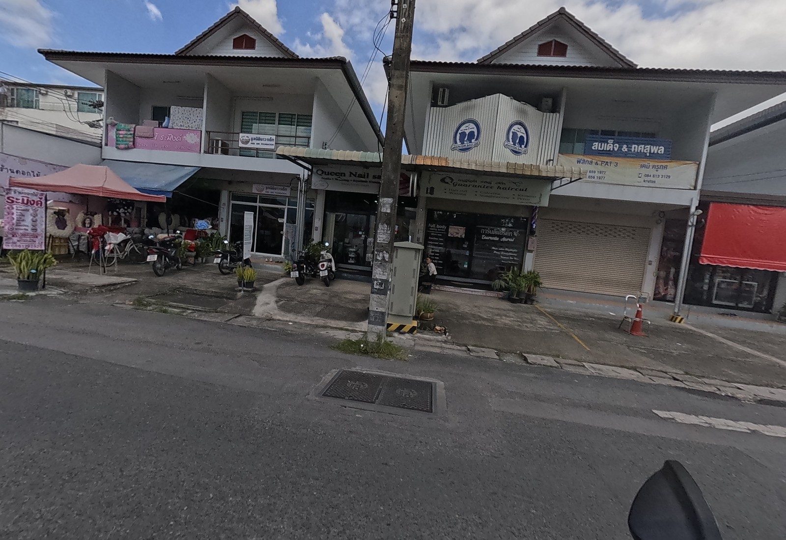 A shophouse row: the Ramingh florist under a pink canopy, the Kids Ark Foundation, Queen Nail, Guarantee Haircut and the physics and chemistry tutor sign.