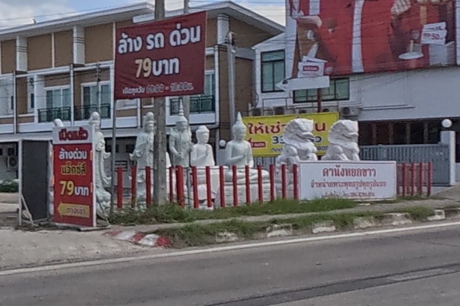 Rows of white stone Buddhas, standing figures and lions at a roadside statue yard