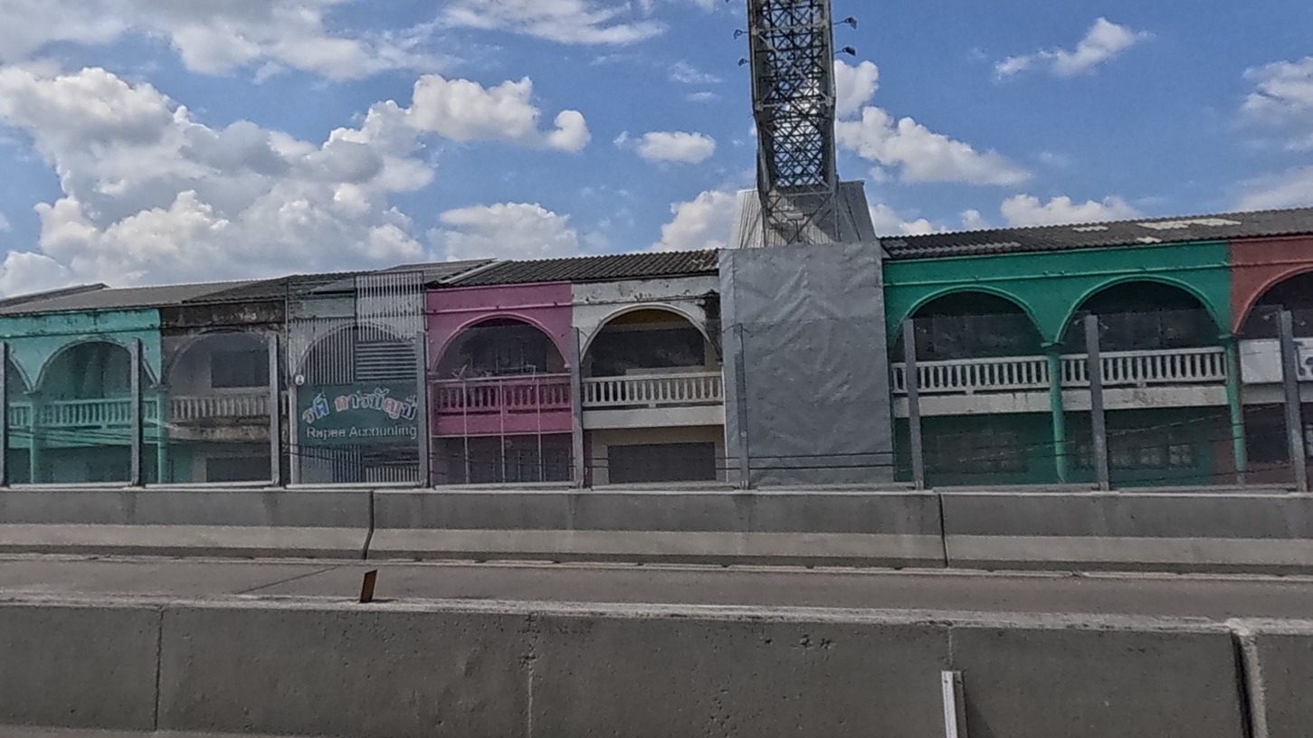 Faded pastel arcaded shophouse row seen from the elevated highway