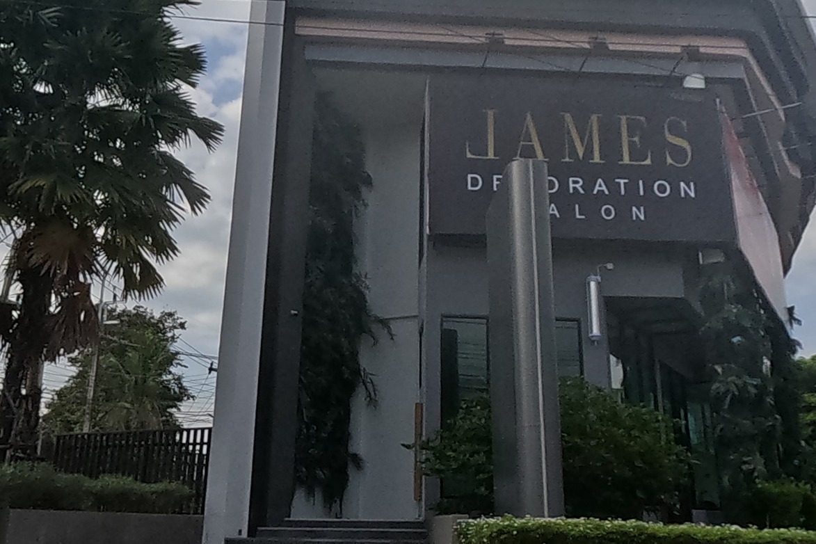 A striking dark modern building with gold lettering reads James Dehydration Salon, fronted by a palm tree and a stepped entrance.