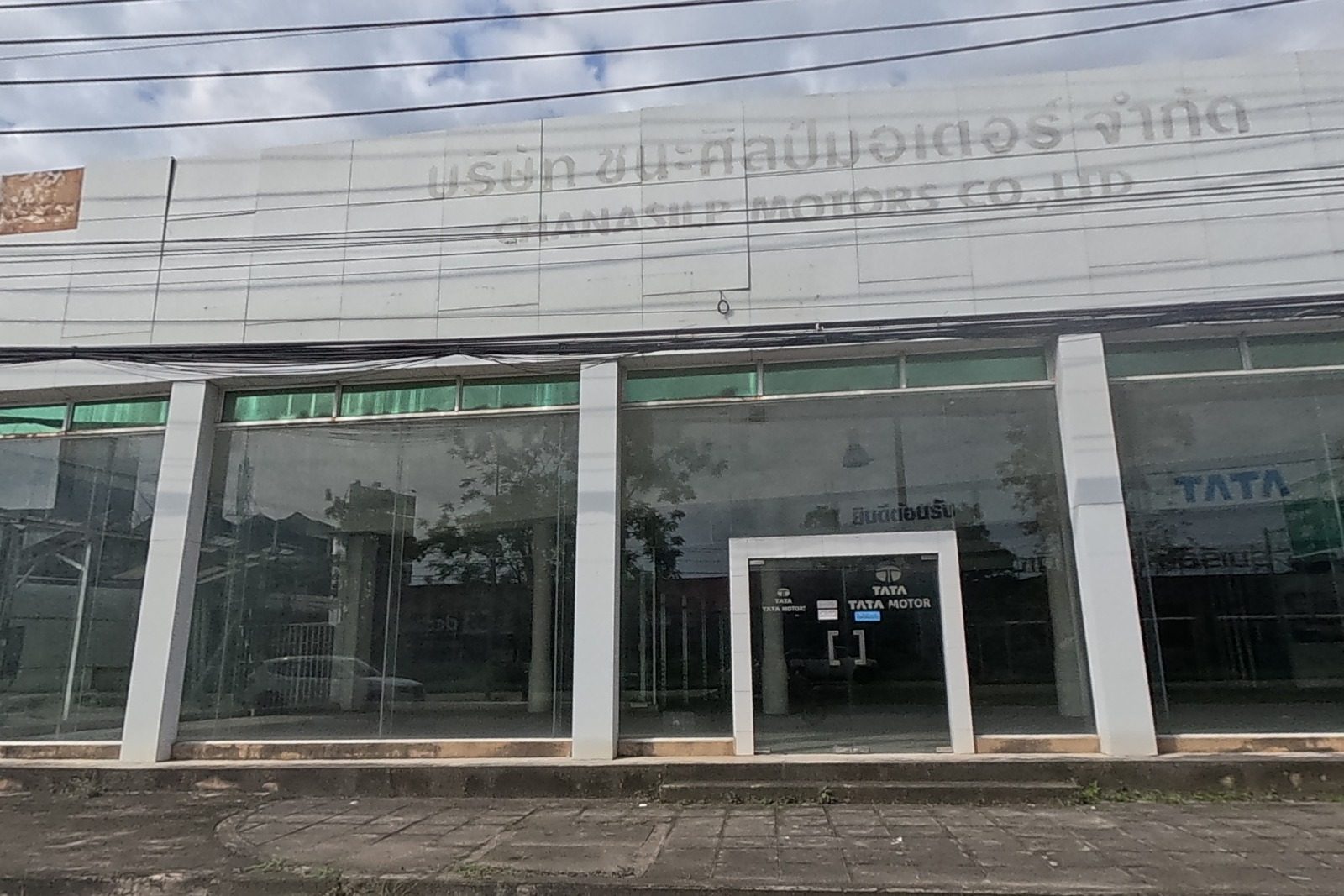 A closed two-storey car dealership showroom with TATA Motors signage on the ground floor and a faded company sign above.