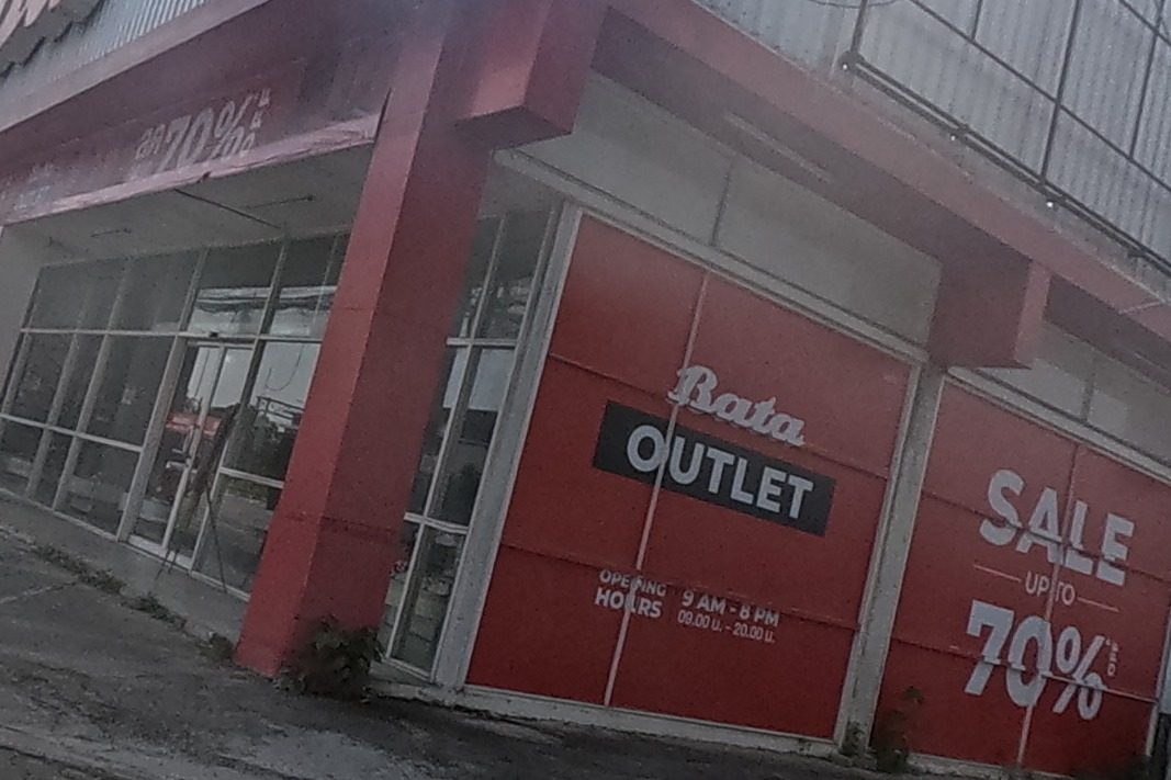 A large Bata Outlet shoe store advertises a sale of up to 70% off, with opening hours 9 AM to 8 PM printed on the shutter and a car parked outside.