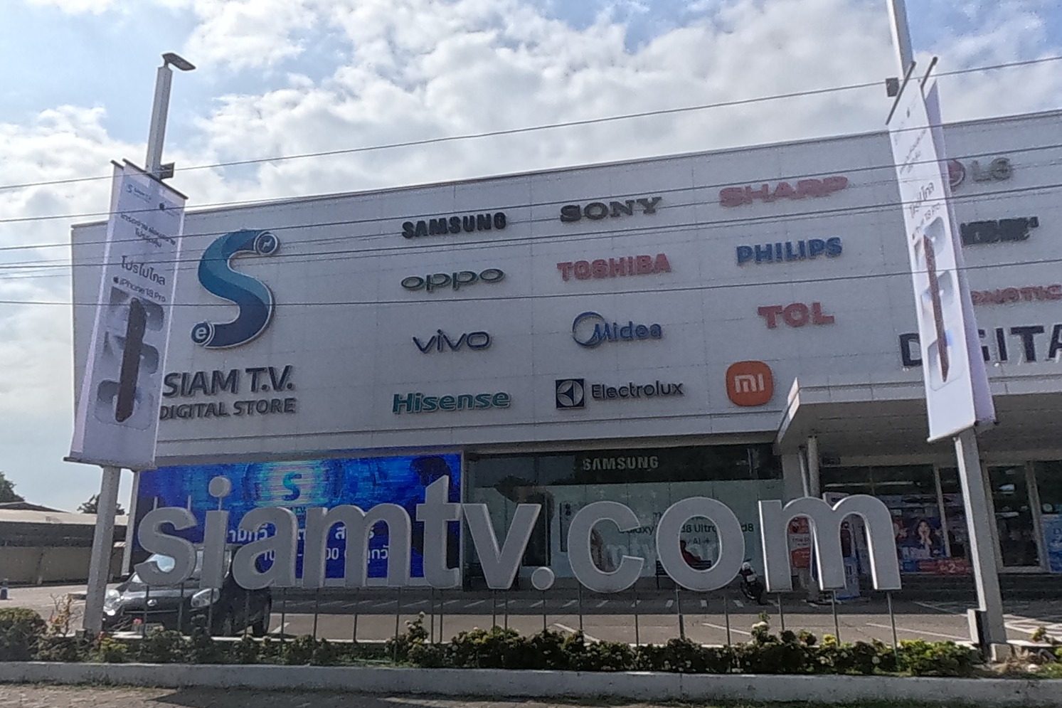 A large Siam T.V. Digital Store spans the block, its facade covered in electronics brand logos above a lit siamtv.com sign.