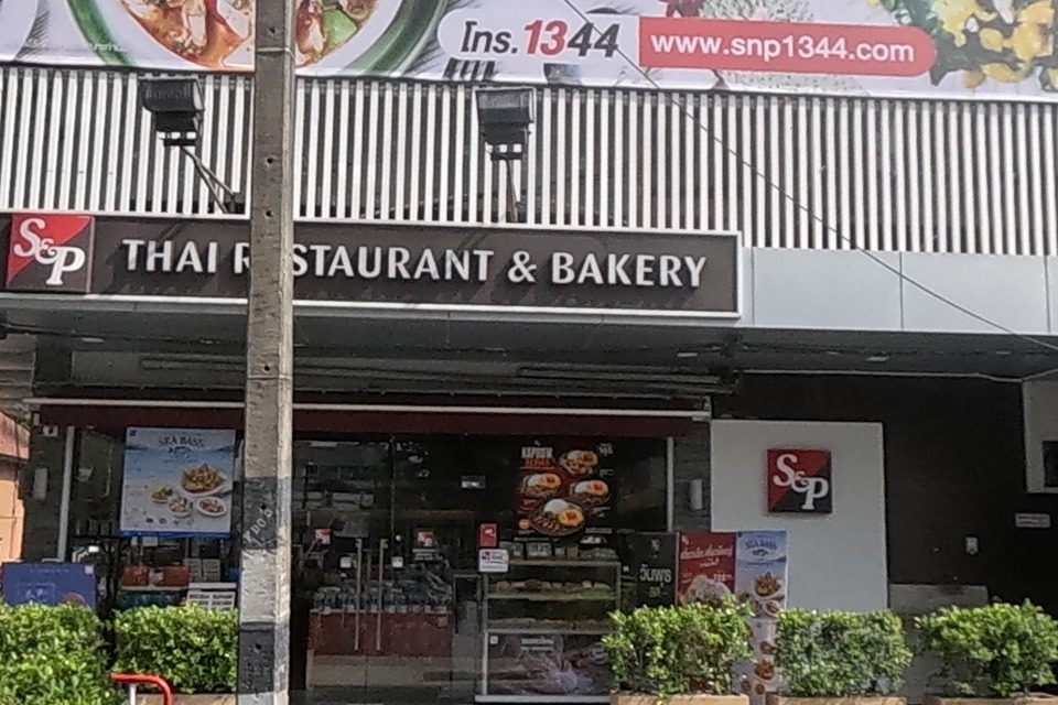 “S&P THAI RESTAURANT & BAKERY” occupies the ground floor of a building with a large food billboard above (hotline 1344, www.snp1344.com).
