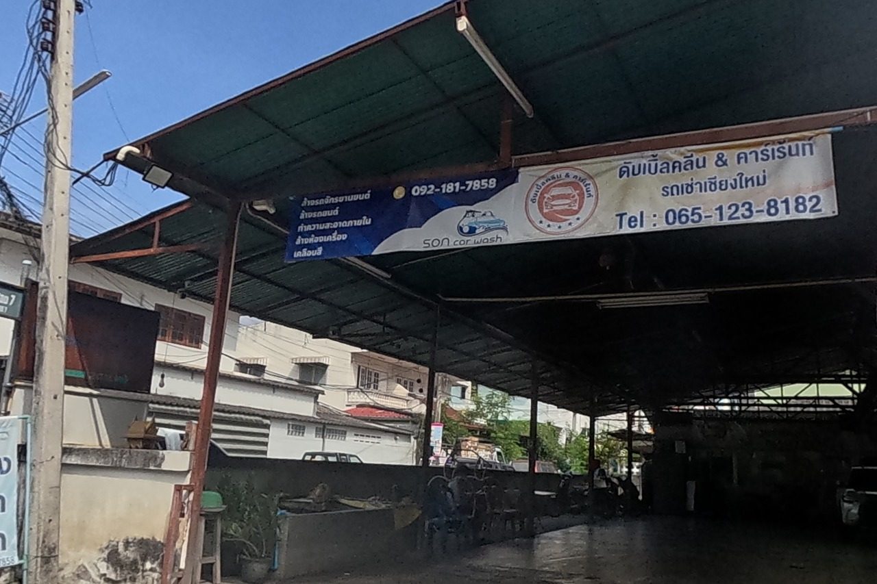 A covered car wash and rental yard, 'SON car wash' / 'ดับเบิ้ลคลีน & คาร์เร้นท์' (Double Clean & Car Rent, tel 065-123-8182 / 092-181-7858), stands beside a small bubble-tea stall selling drinks at 25 baht.