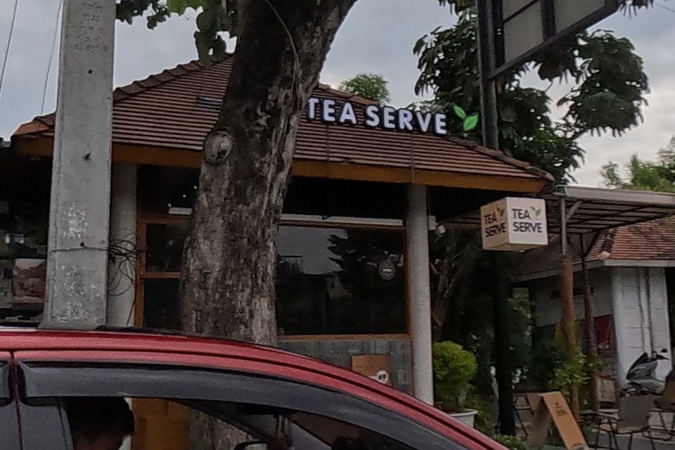 A red car alongside; behind it a closed shophouse and the Tea Serve cafe with a CLOSED sign board.