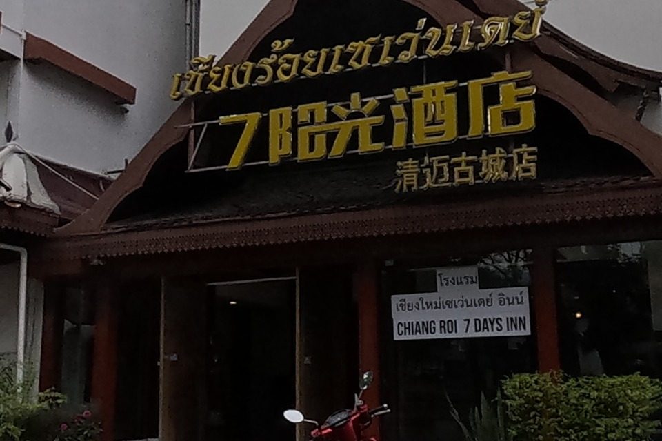 'Chiang Roi 7 Days Inn' (เชียงร้อยเซเว่นเดย์ / 7阳光酒店), signed in Thai, Chinese and English, occupies a traditional Lanna-roofed building; next door 'Tokyo Magic Roll' sells Japanese-style dessert crepes.