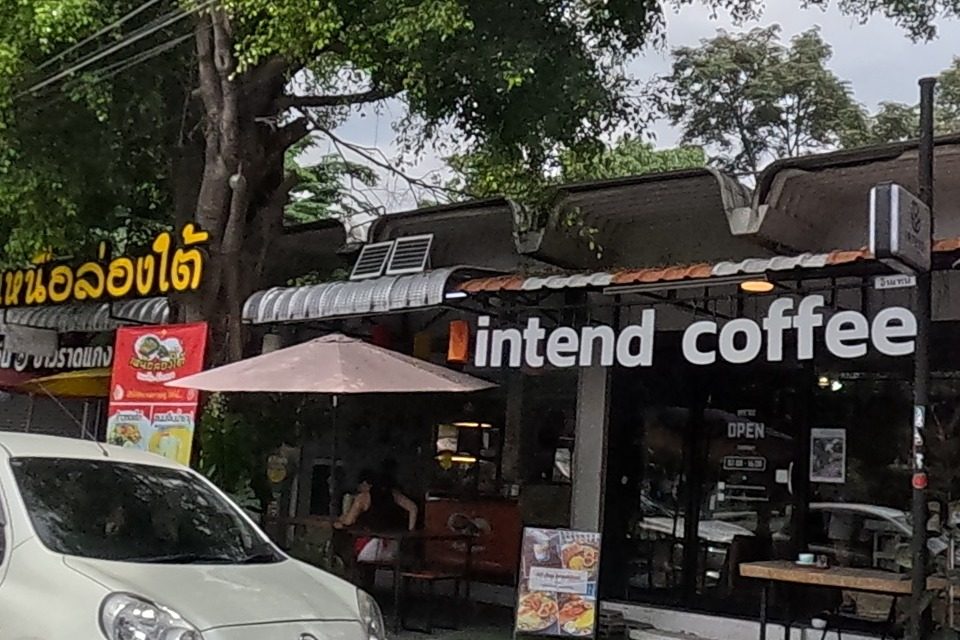 'intend coffee' cafe next to a noodle shop advertising tom-yum lime noodles, and a further stall advertising basil stir-fry and shrimp pad thai.