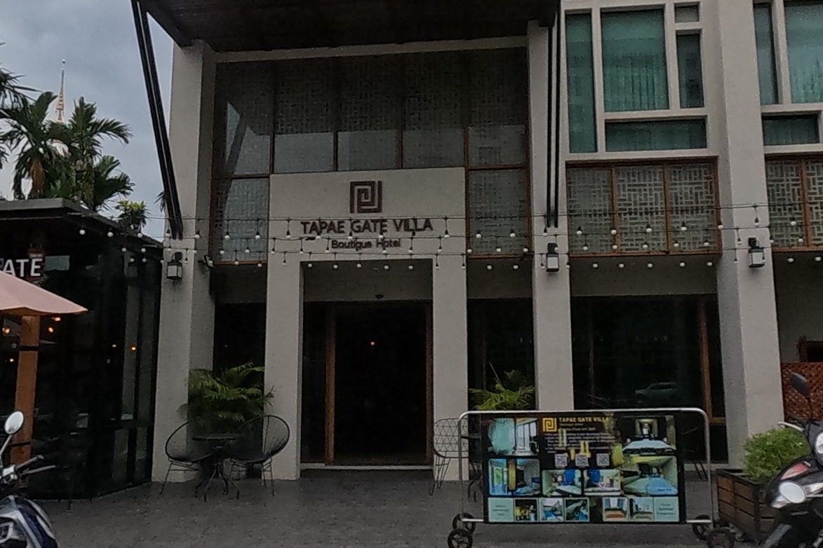 A boutique hotel and its streetside cafe stand at the corner, scooters parked out front.