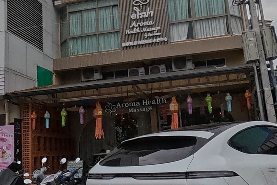A health massage shop decorated with paper lanterns sits beside a blue pharmacy building.