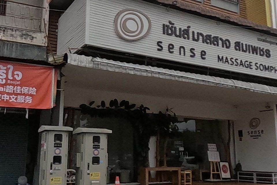 A massage shop and a row of shuttered shopfronts covered in ad banners at the corner.