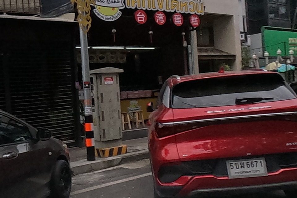 A Taiwanese egg-cake bakery stall beside a restaurant strung with red lanterns under traditional gabled roofs.