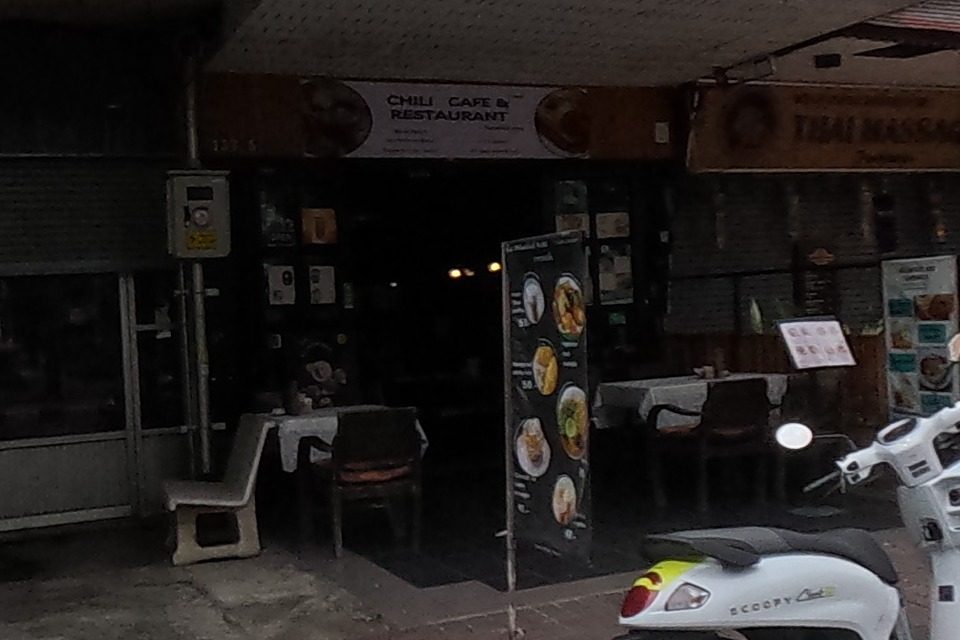 A cafe and restaurant under a modern building, illustrated menu boards standing outside.