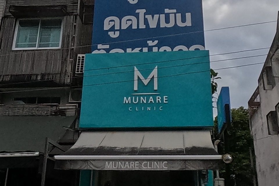A teal-fronted aesthetic clinic sits beside a boutique hotel sign, with an old grey gabled house further along the row.