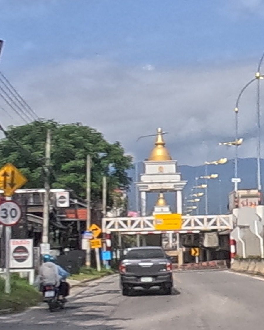 Temple gate with a gold chedi against the sky
