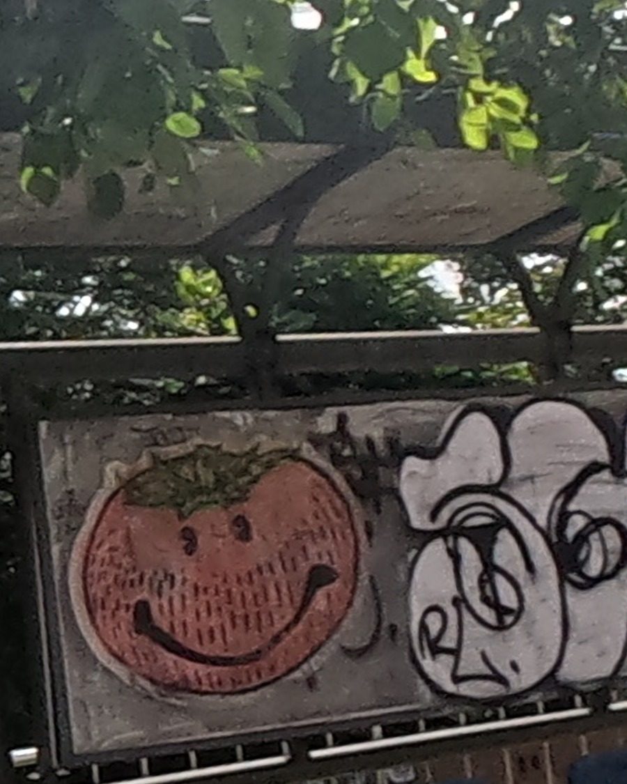Grinning tomato graffiti on a bus shelter