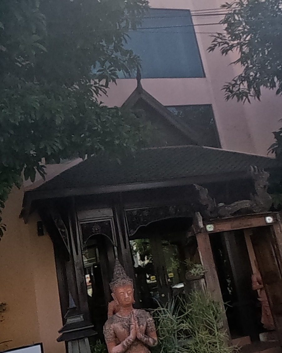 Praying deity statue at a teak spa gate