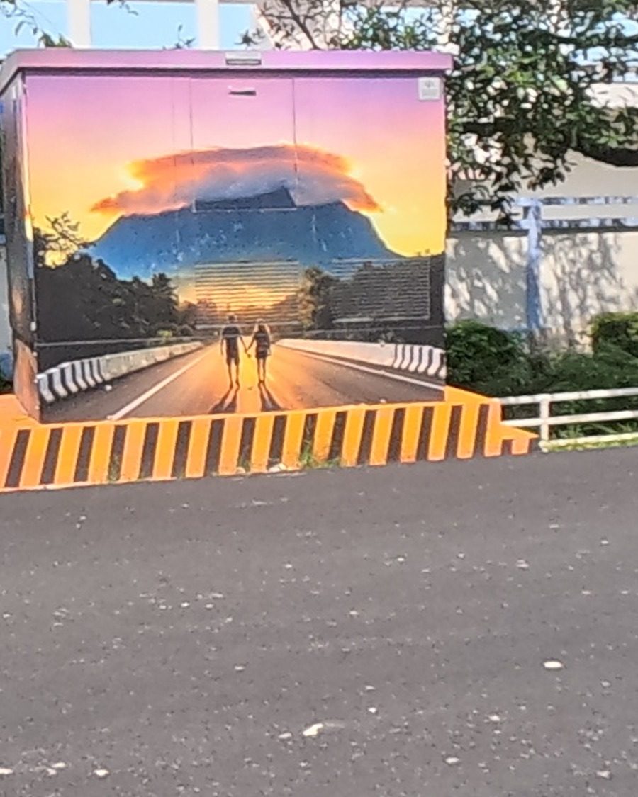 Mountain-sunset mural on a roadside utility box