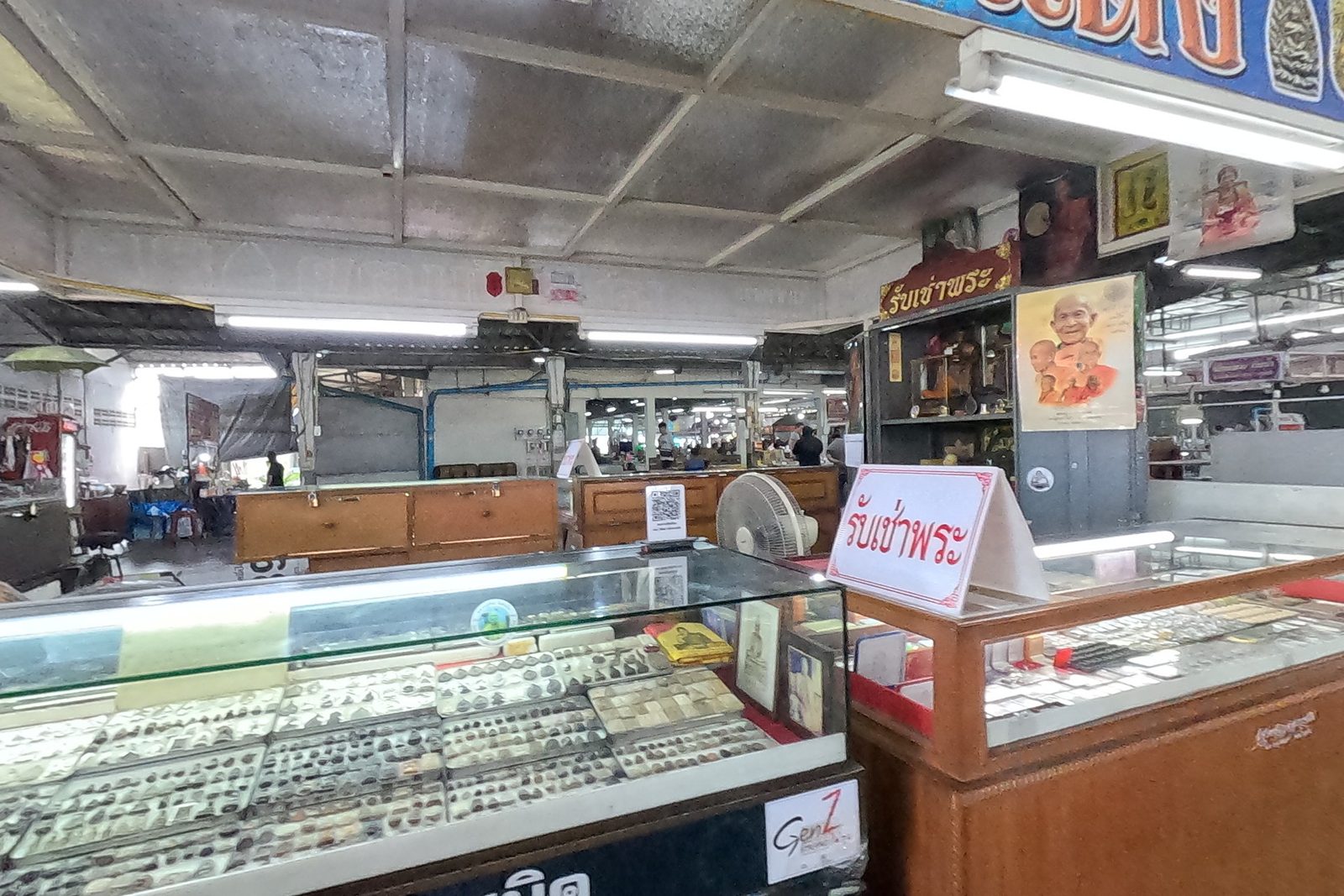Inside an amulet shop: glass counters and a รับเช่าพระ card