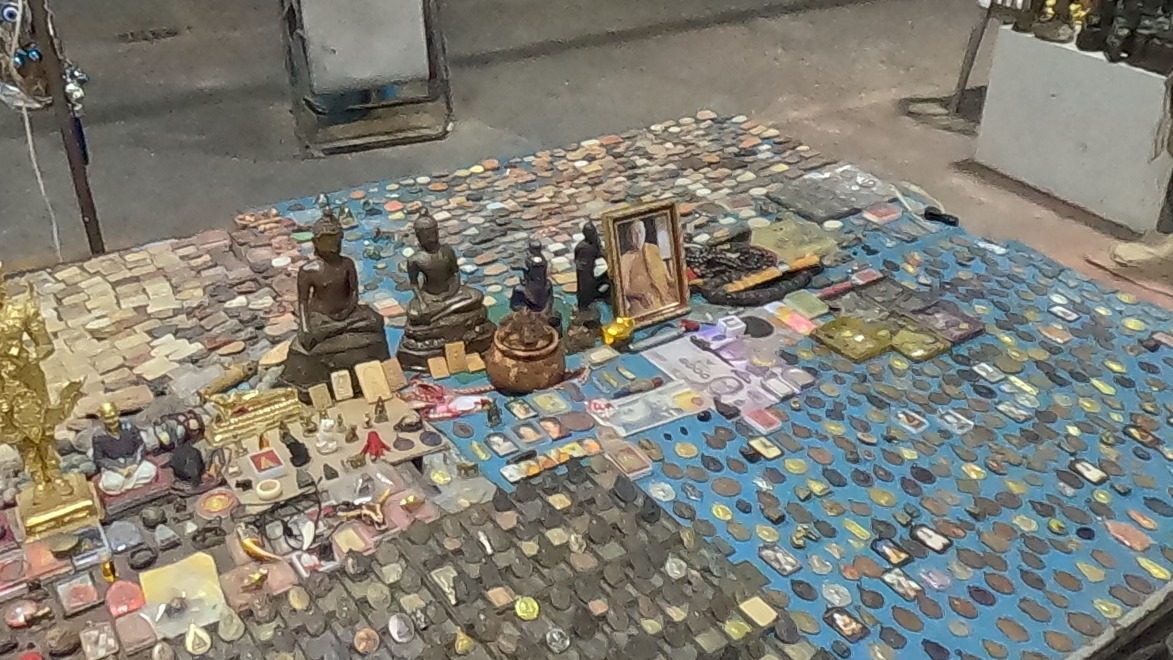 A table of coin amulets, tablets and small Buddha images