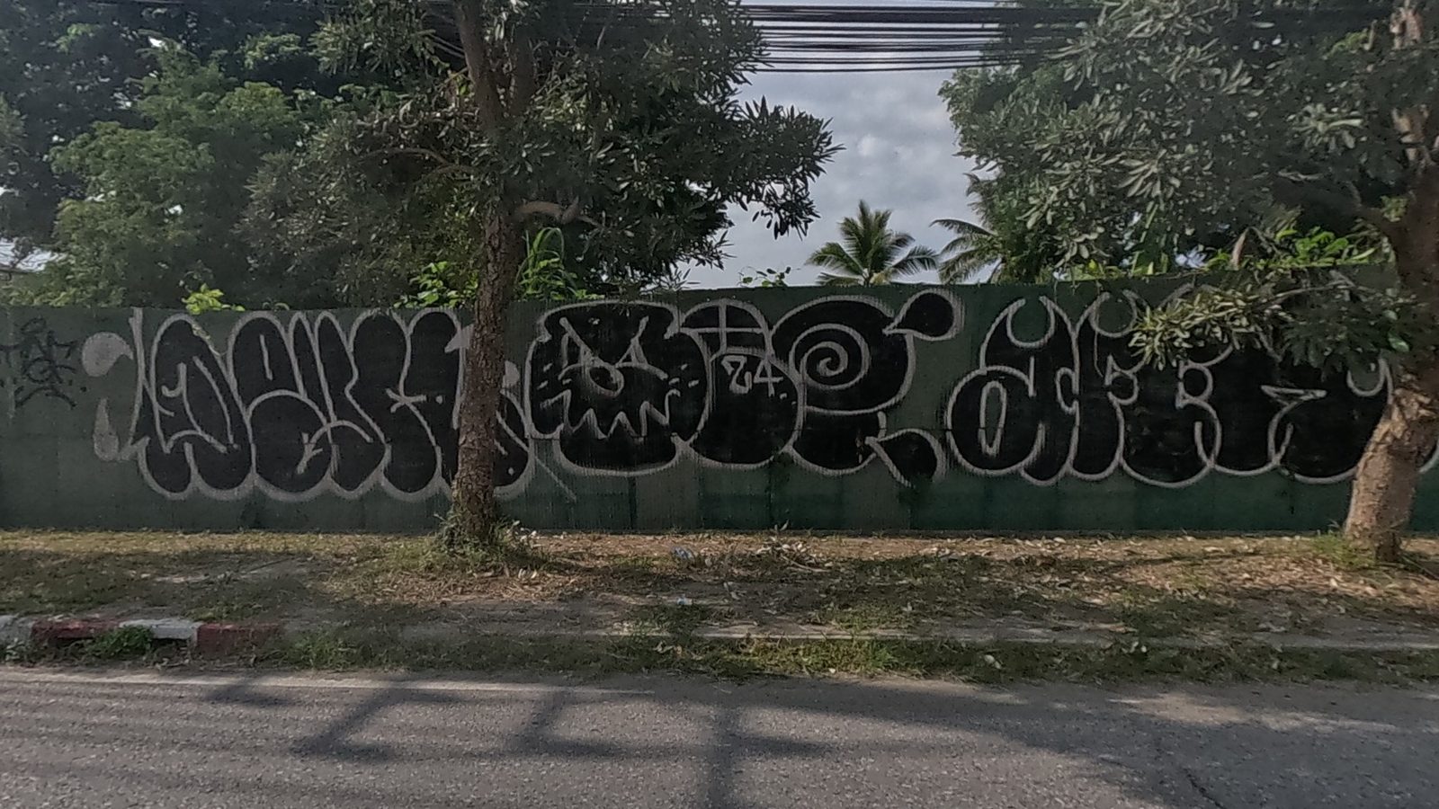 black and white bubble-letter throw-up with a cartoon face, roadside wall