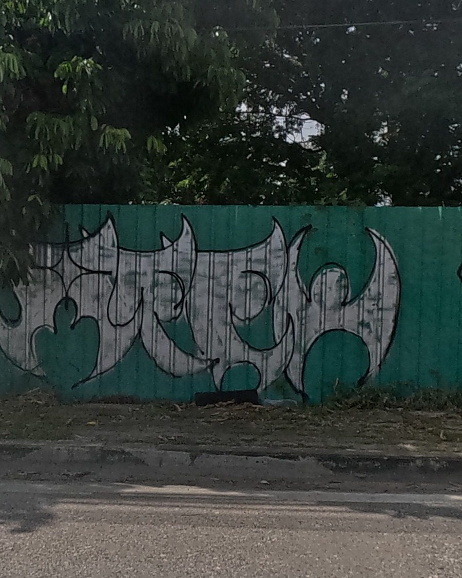 silver winged/moon-shape graffiti piece on a green fence