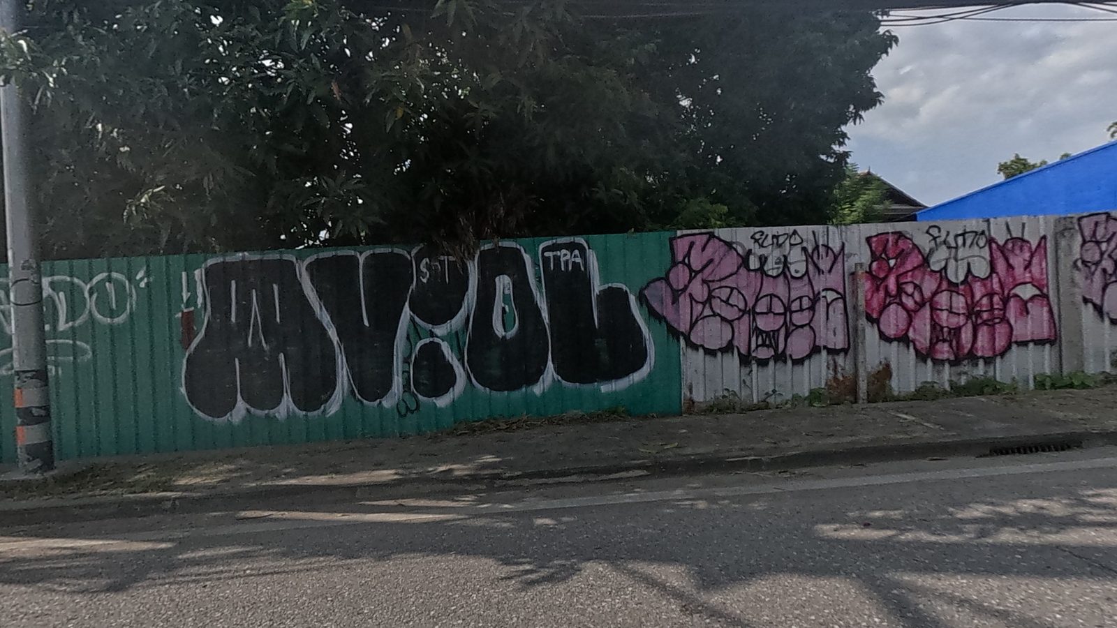 row of black and pink throw-ups on a corrugated fence