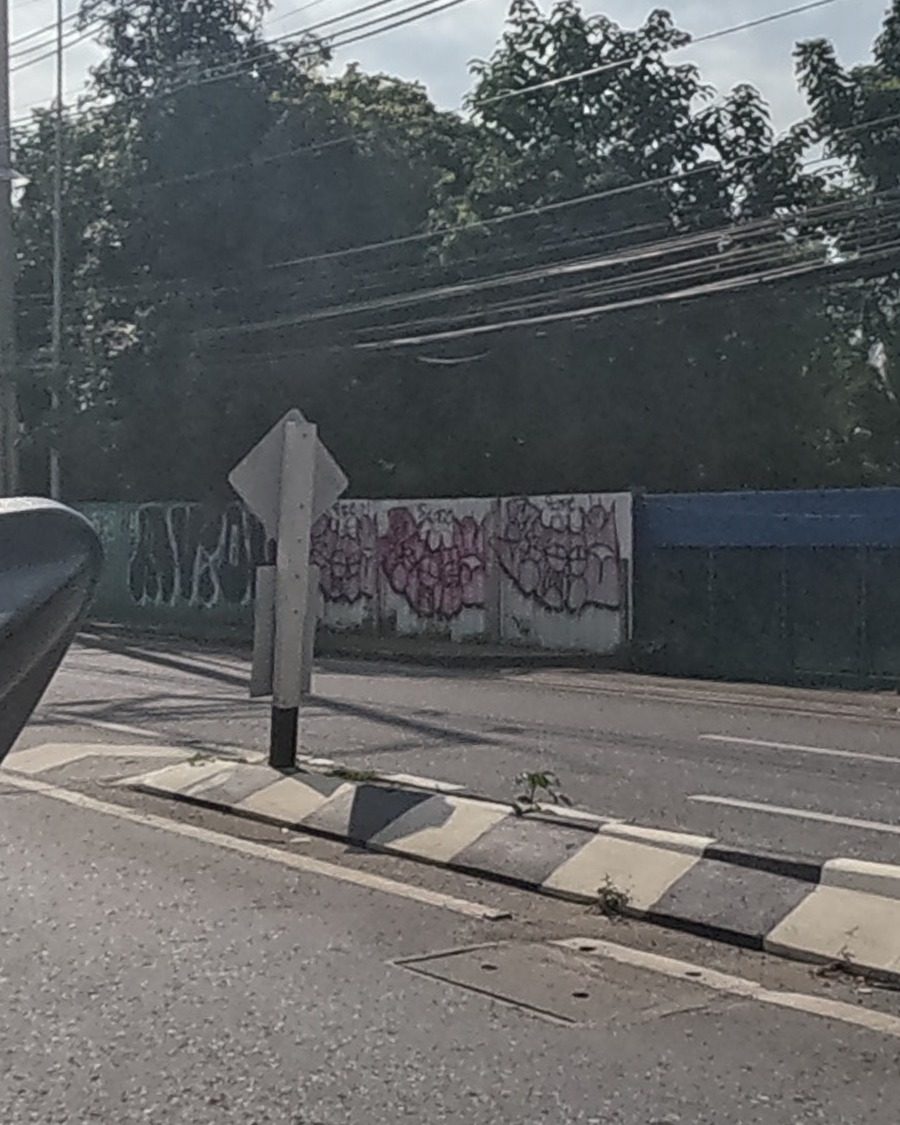 faded pink and black tags on a low wall by a tyre shop